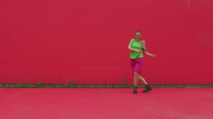 跳舞的年轻快乐女孩在红墙上表演充满活力的表现力舞蹈。现代快乐女舞者酷动人