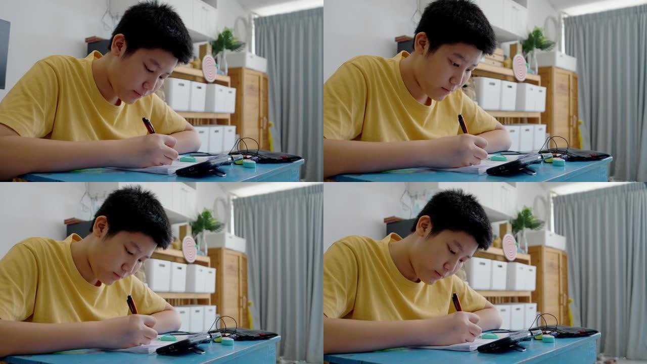 亚洲男孩在家学习在线课程时做作业，社交疏远生活方式理念。