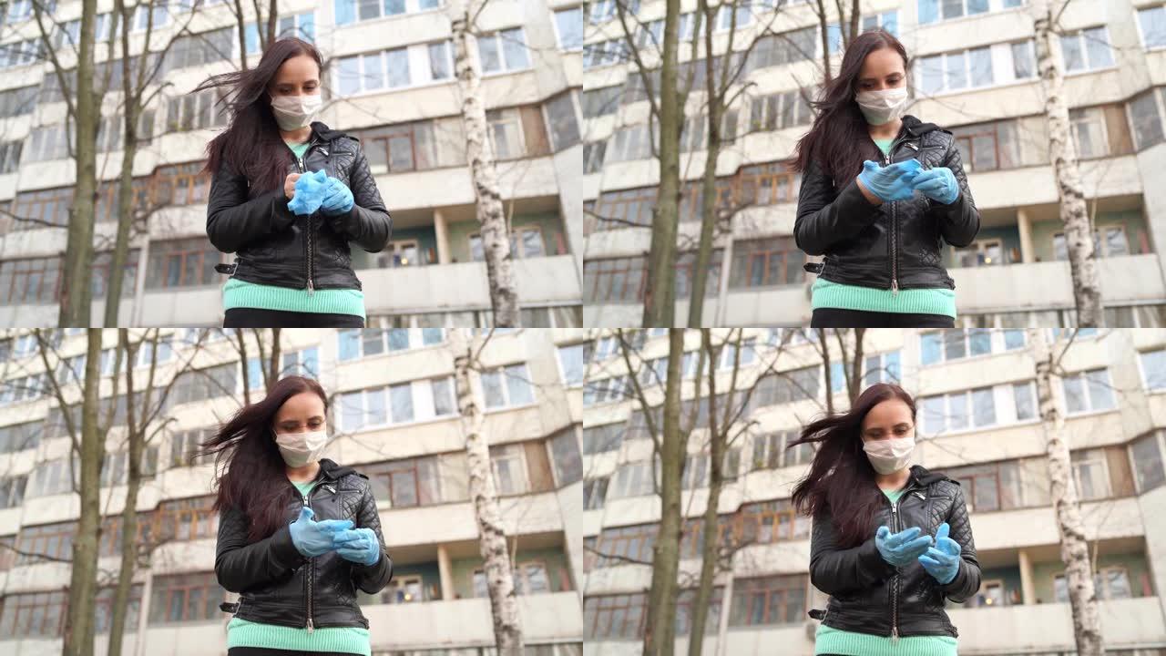 戴着医用面具的年轻女子在街上戴上医用手套。女性在行走中保护自己免受疾病侵害的特写镜头。冠状病毒流行感