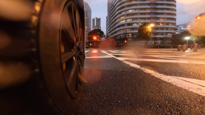 在雨夜开车穿过城市。汽车车轮的特写。红灯停了下来