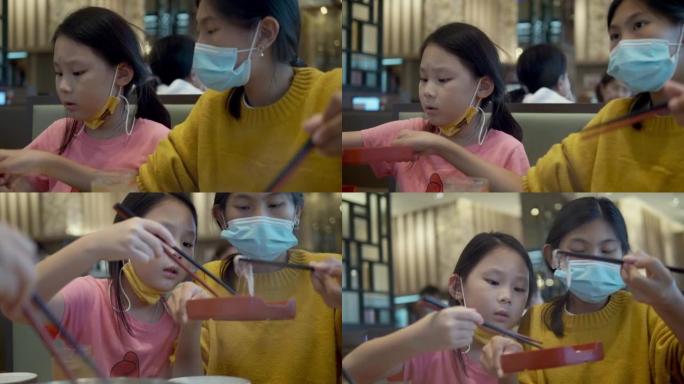 亚洲儿童在餐厅里吃sha锅 (Sukiyaki) 或火锅日本料理，并与家庭，生活方式相结合。