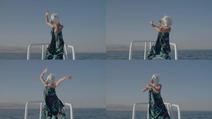 欢快的人在独角兽头面具在游艇鼻子上跳舞。海上船上独角兽面具的有趣舞蹈。假期快乐。