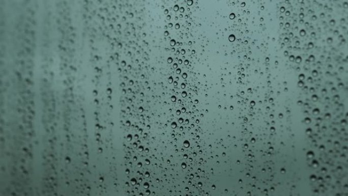玻璃上的水滴特写镜头，雨滴在黄昏时撞击窗玻璃。