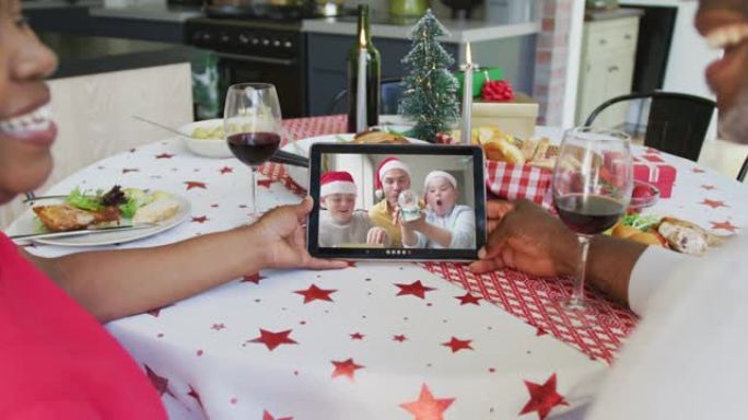 微笑的非洲裔美国夫妇使用平板电脑与家人在屏幕上进行圣诞节视频通话