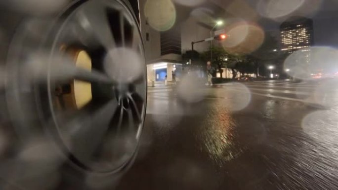 在雨夜开车穿过城市。汽车车轮的特写。在被人穿过的十字路口右转