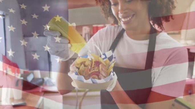 非裔美国妇女微笑着准备热狗，挥舞着美国国旗