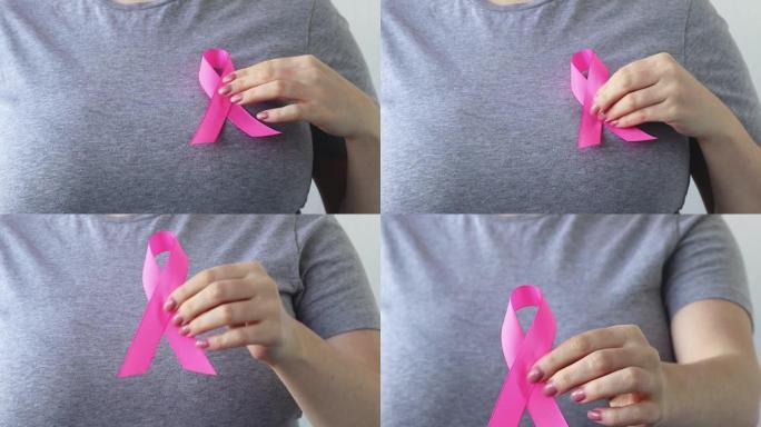 乳腺癌宣传月。一位女士在她的t恤上系上粉红色的丝带。支持的概念。促进抗癌运动。