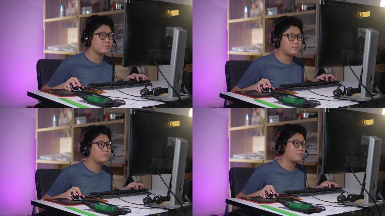 亚洲男孩戴着眼镜、耳机，晚上在家用电脑玩网络游戏，生活理念。