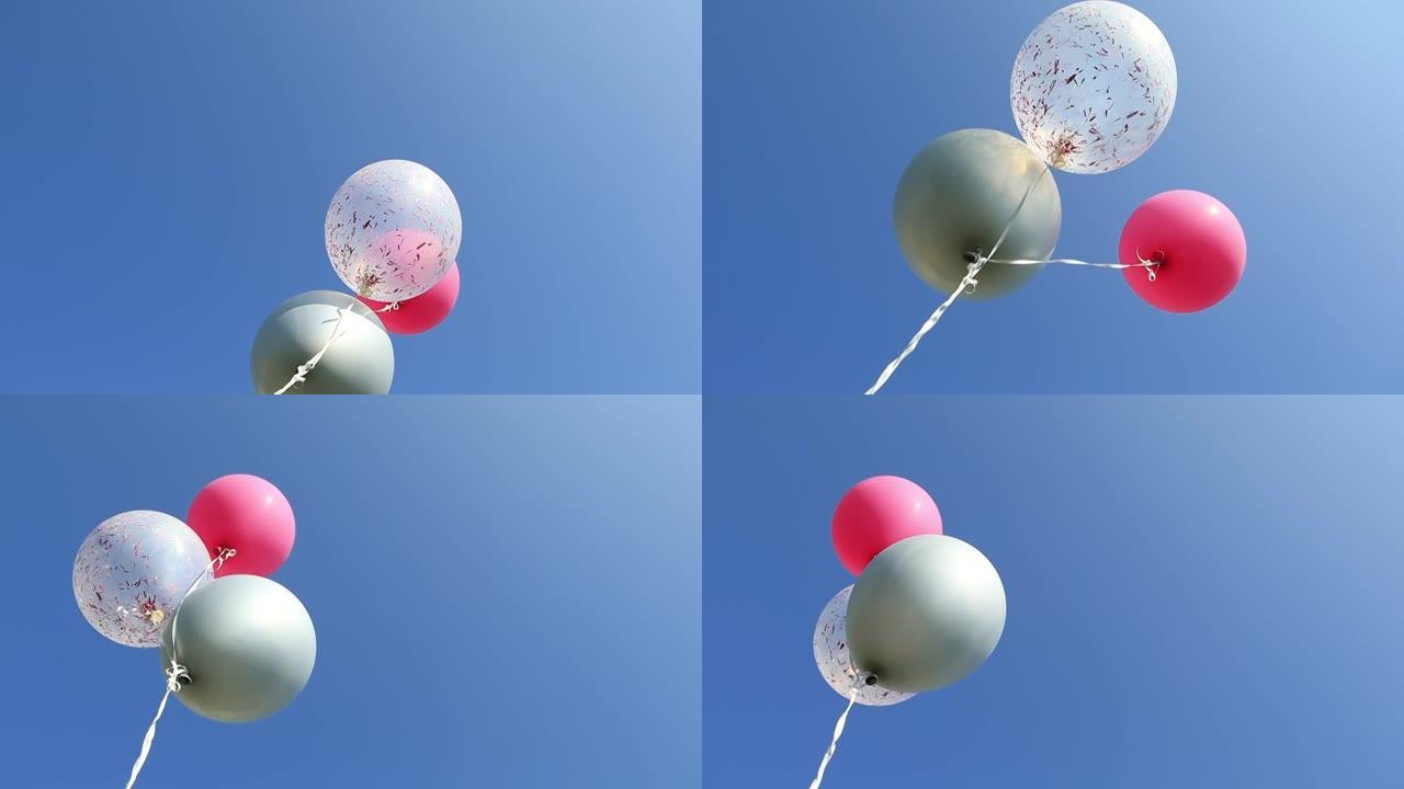 三个彩色氦气球漂浮在蓝天上。生日庆典。