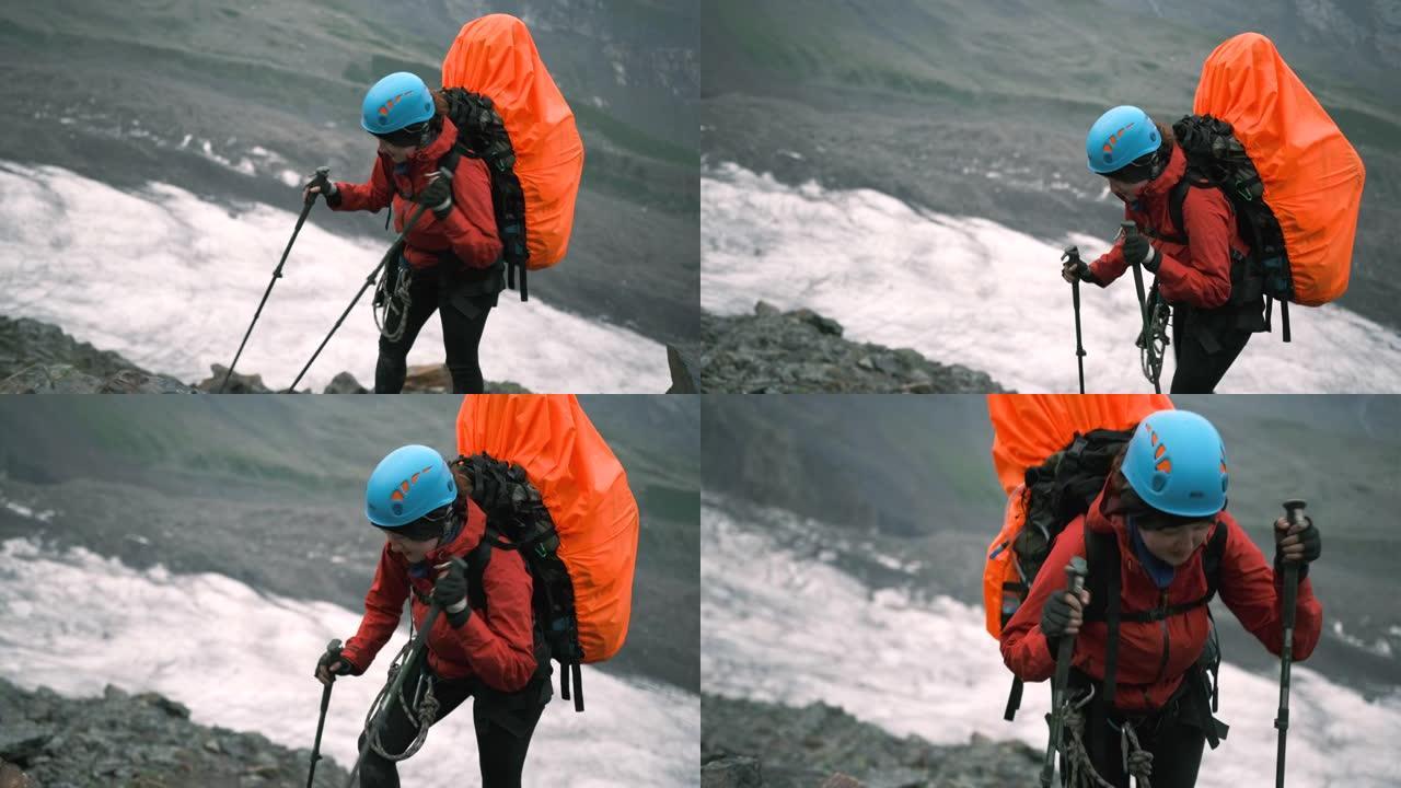 山上的一名妇女带着一个装有装备和登山杖的大背包爬上去
