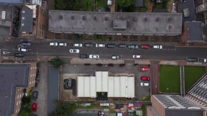 空中鸟瞰头顶向下跟踪汽车的视图让位于狭窄的城镇街道上迎面而来的交通。英国伦敦