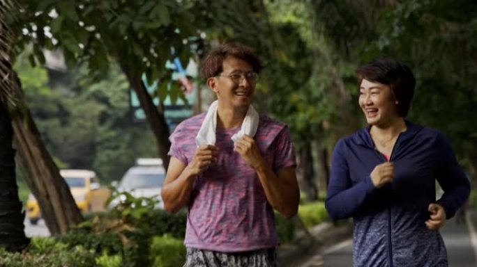 一群亚洲人在夏天的早晨在公园里快乐地慢跑。每天跑步的男人和女人都有健康的身体。假日周末活动，为城市人