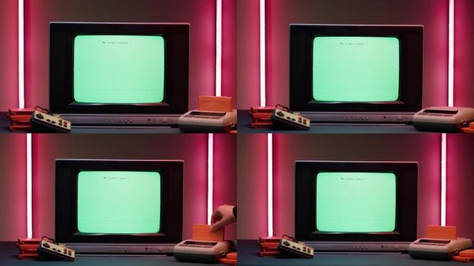 红色霓虹灯背景上带有蓝屏的旧电视。老式电视和复古playstation的特写镜头，更换墨盒。古董视频