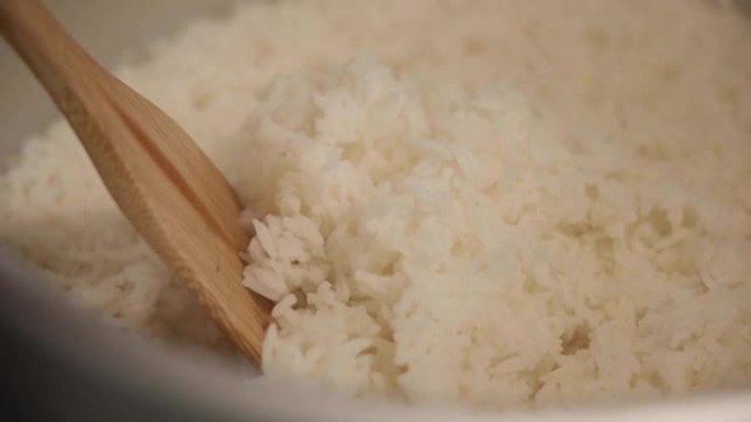 茉莉花米饭用蒸汽在电饭煲中烹饪，用木勺舀熟米饭