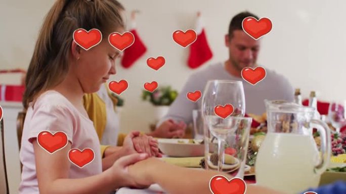 圣诞节晚餐时，在快乐的高加索家庭上漂浮的心脏动画祈祷