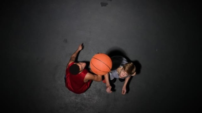 篮球比赛开始前掷界外球的俯视图。两名对方球员为控球而跳跃。慢动作