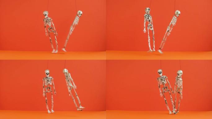 悬挂的骨骼在橙色背景上跳舞。准备万圣节派对。