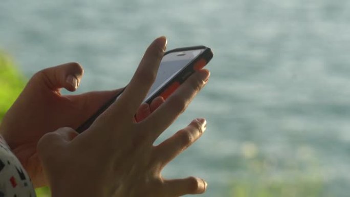日落时在海滩上使用手机的妇女
