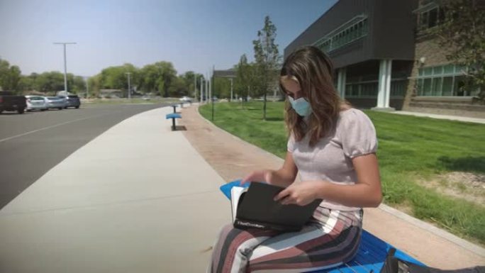 十几岁的女性坐在公立学校大楼外的公共汽车站，戴着口罩，执行任务，回到学校4k视频系列
