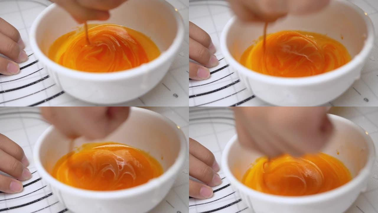在糖衣碗中手工混合橙色，用于装饰万圣节饼干，生活方式概念。
