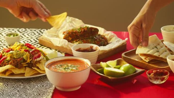 吃传统的墨西哥食物，德克萨斯墨西哥菜。双手从木托盘中取出煮熟的玉米饼，将玉米片浸入酱汁中，番茄汤配香