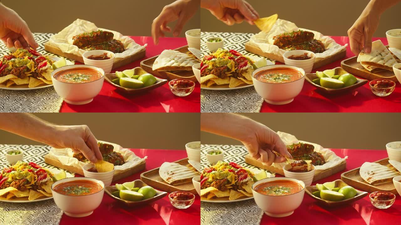 吃传统的墨西哥食物，德克萨斯墨西哥菜。双手从木托盘中取出煮熟的玉米饼，将玉米片浸入酱汁中，番茄汤配香