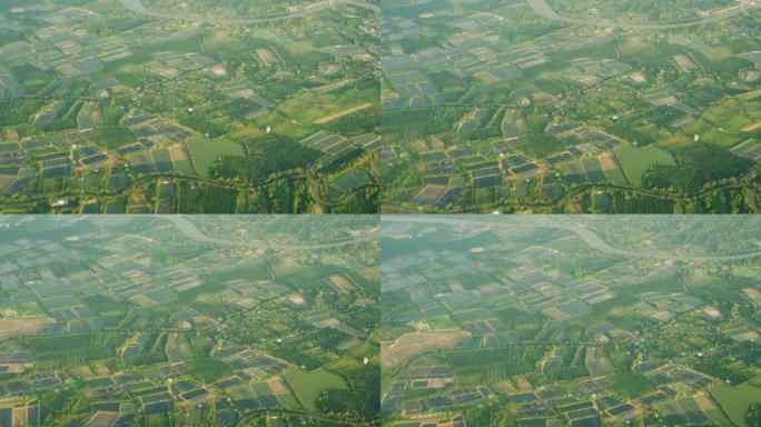 从绿色和黄色稻田住宅郊区上方的飞机窗户上的景色