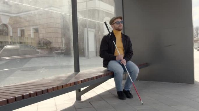 一个盲人坐在城市的长椅上
