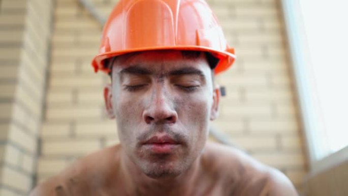 戴着安全帽的肮脏建筑工人的肖像。下班后疲倦的建筑商。