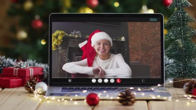 快乐的白人妇女在笔记本电脑上进行视频通话，带有圣诞节装饰和树木