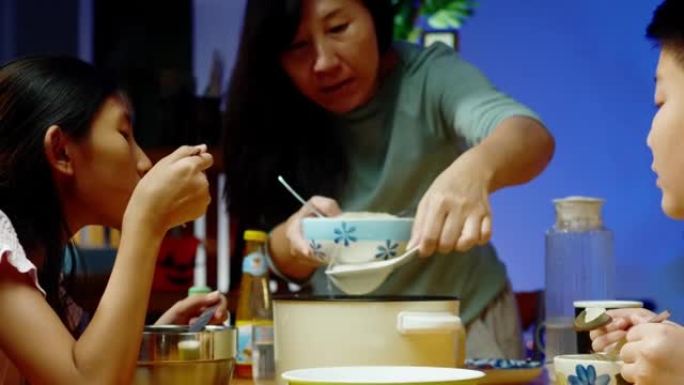 亚洲家庭的母亲和孩子在晚上在家一起吃sha锅或寿喜烧，生活方式的概念。