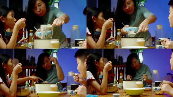 亚洲家庭的母亲和孩子在晚上在家一起吃sha锅或寿喜烧，生活方式的概念。