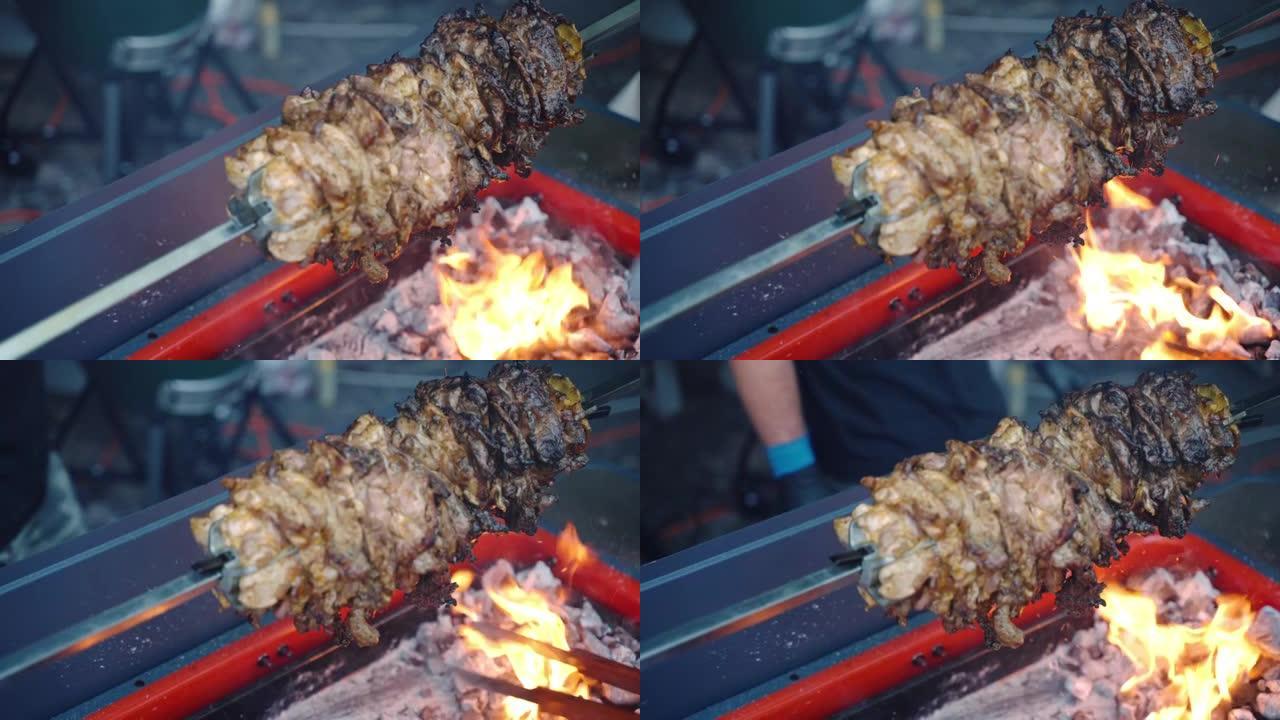 旋转烧烤串的俯视图镜头，在热的炭灰中加入脂肪猪肉，燃烧的火烤多汁的肉，用于野餐派对。烤肉吐在燃烧的火