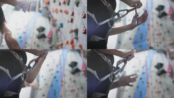 运动女运动员固定安全绳、登山扣钩。将护网连接到登山扣上。在室内健身房独自攀登。慢动作
