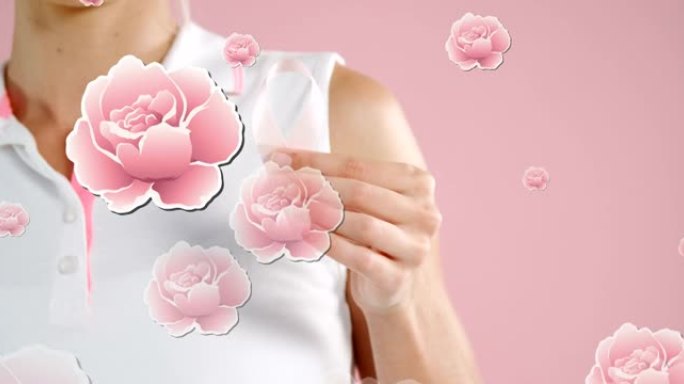 粉红玫瑰漂浮在手持乳腺癌丝带的女人的手上，在粉红色