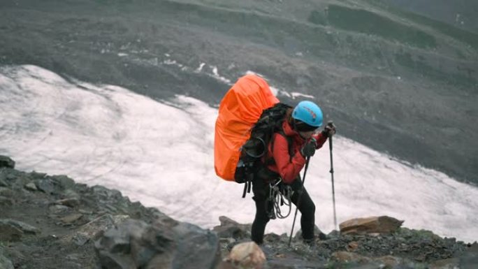 山里的一名妇女带着一个装有装备和登山杖的大背包爬上去。