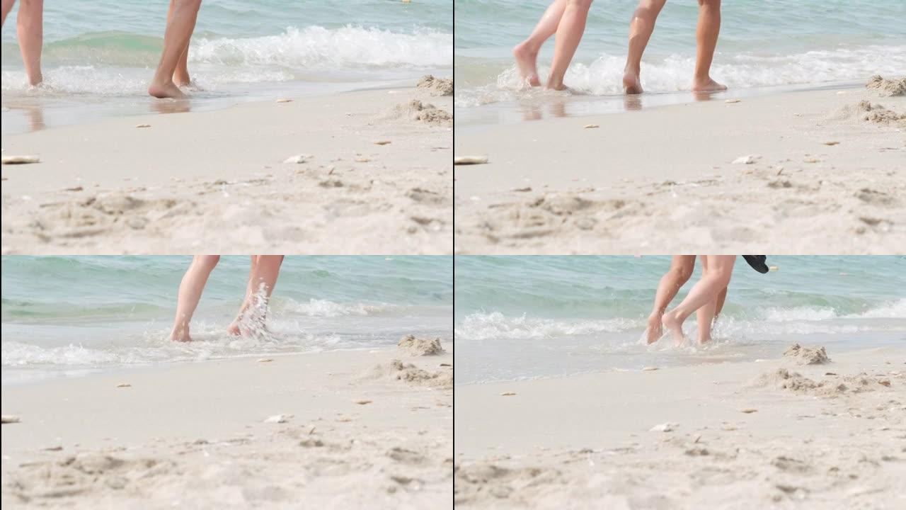 赤脚情侣双脚在海滩海水上行走。暑假，假期，家庭旅行。温暖国家的情侣游客