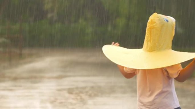 亚洲小女孩在雨中玩水。