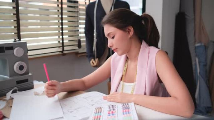 专业女性设计师或裁缝通过扔画纸看起来很忙，对工作和行动感到不安，她在窗户附近的工作场所房间工作