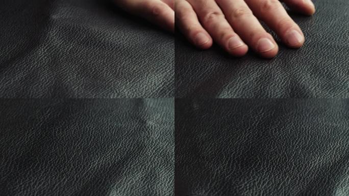 用手特写触摸黑色皮革，生产由真皮或人造革制成的手工配件。工作场所的动物皮肤材料，质量控制