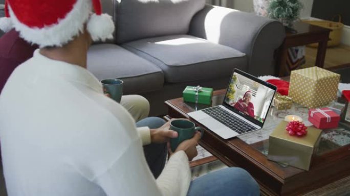 混血儿父子使用笔记本电脑进行圣诞节视频通话，屏幕上有幸福女人