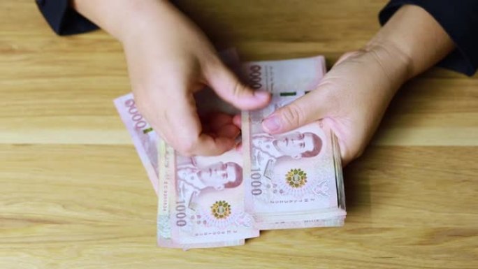 枪手的手在数着泰国的钱。