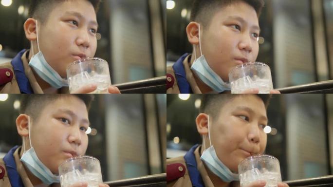 快乐的亚洲童子军制服在美食广场享受他的饮料，生活方式理念。