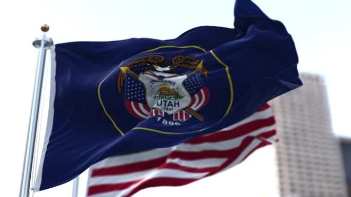 美国犹他州的国旗迎风飘扬，背景是模糊的美国星条旗。
