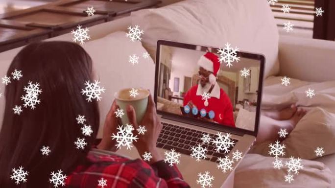 圣诞节期间，雪花落在拿着咖啡杯的女人身上，在笔记本电脑上放着录像带