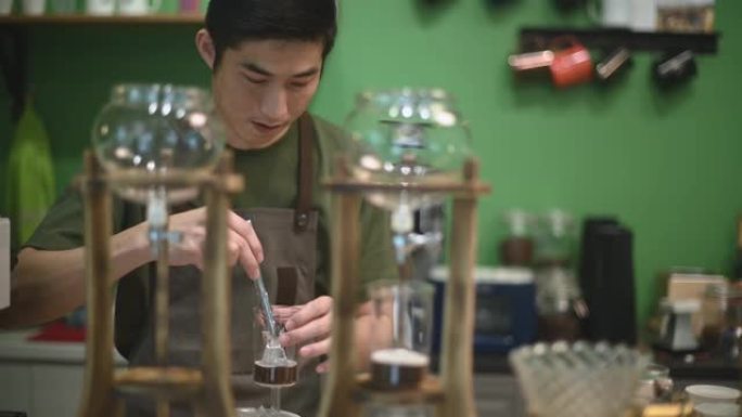 亚洲中国男咖啡师在咖啡馆咖啡店准备冷冲泡冰滴咖啡加冰块