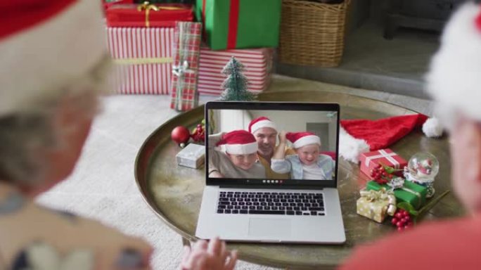 白人高级夫妇使用笔记本电脑进行圣诞节视频通话，屏幕上有微笑的家人