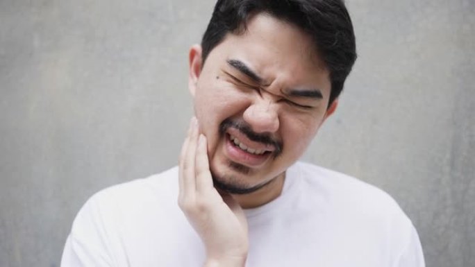 慢动作场景成人中东男子用手按摩脸颊因牙痛 (智齿) 孤立在灰色背景上牙齿保健概念