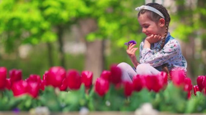 快乐的女孩在城市公园享受美丽花园的香气和色彩。春天的郁金香。