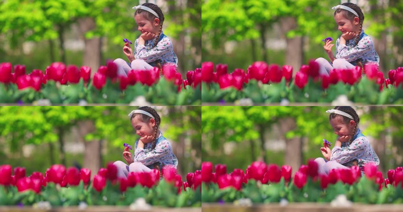 快乐的女孩在城市公园享受美丽花园的香气和色彩。春天的郁金香。